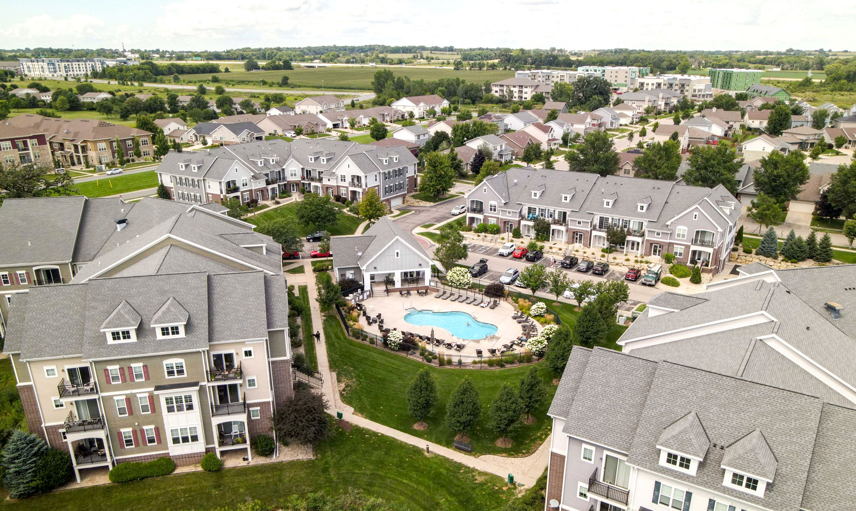 Aerial view of a modern multifamily residential community featuring landscaped grounds, a central pool area, and a mix of apartment buildings, highlighting Wangard Partners' investment in the Midwest multifamily market.