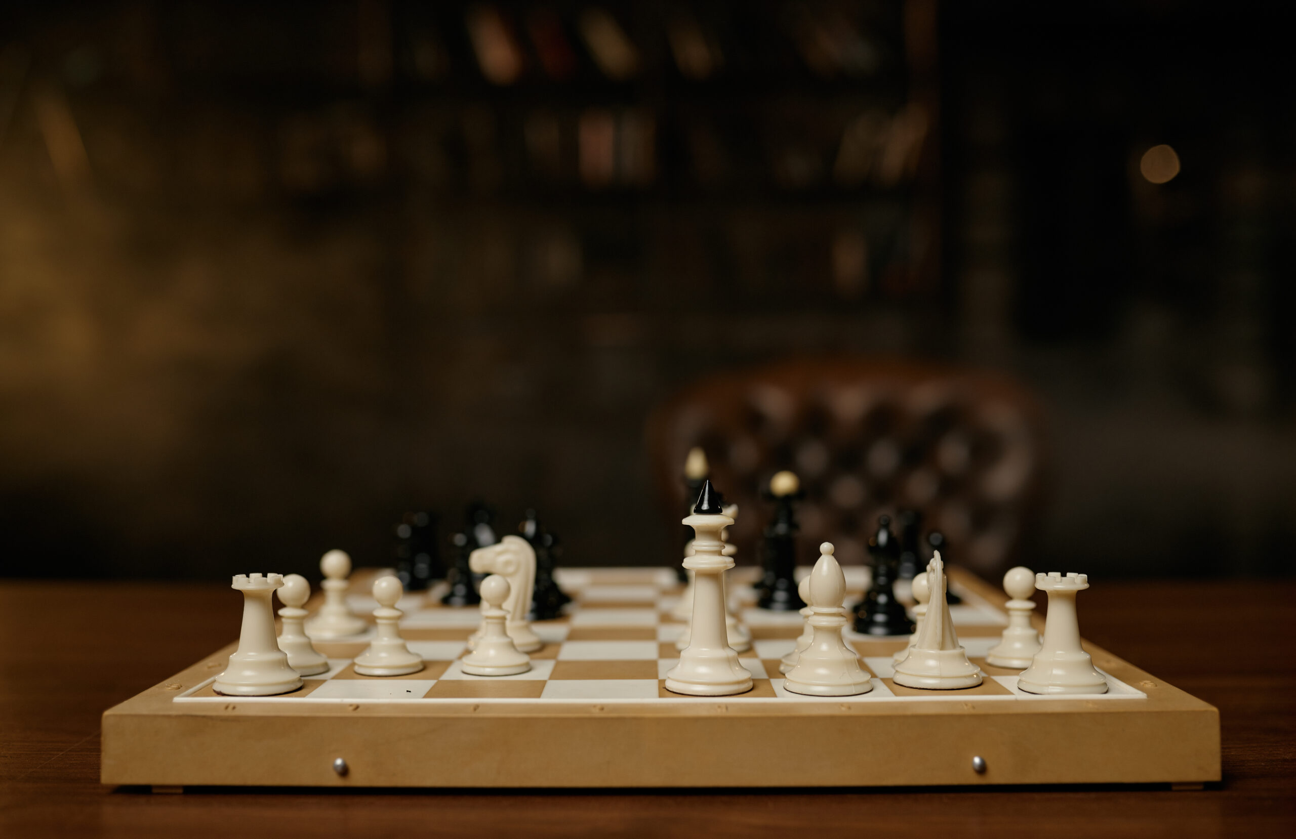 A wooden chess board with white and black wood chess pieces